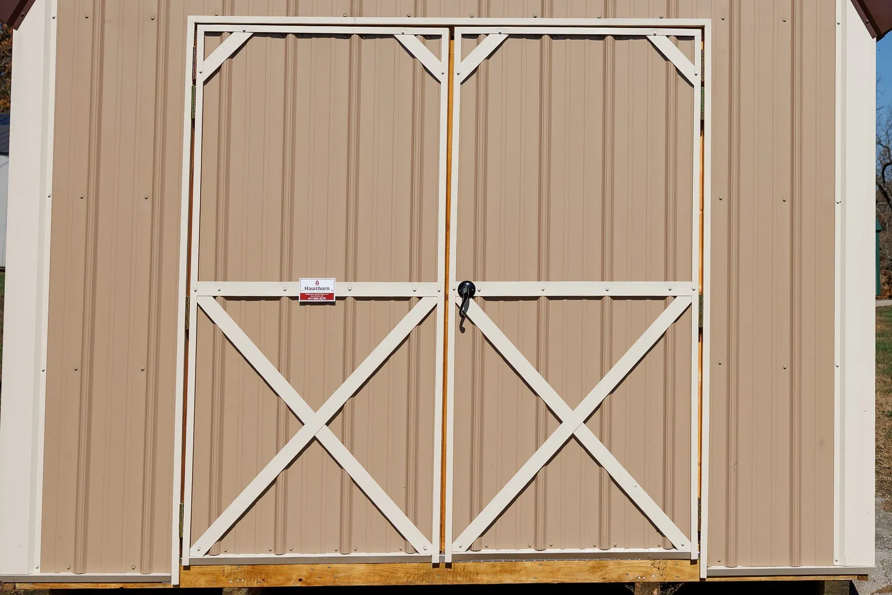Double doors with cream X-trim and a locking handle on a tan barn