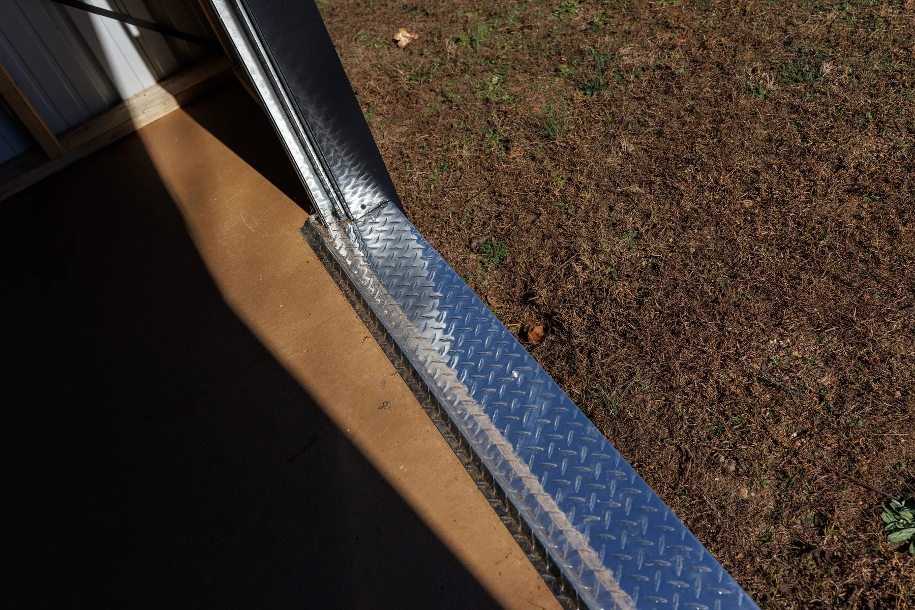 The aluminum diamond-plate threshold at a doorway