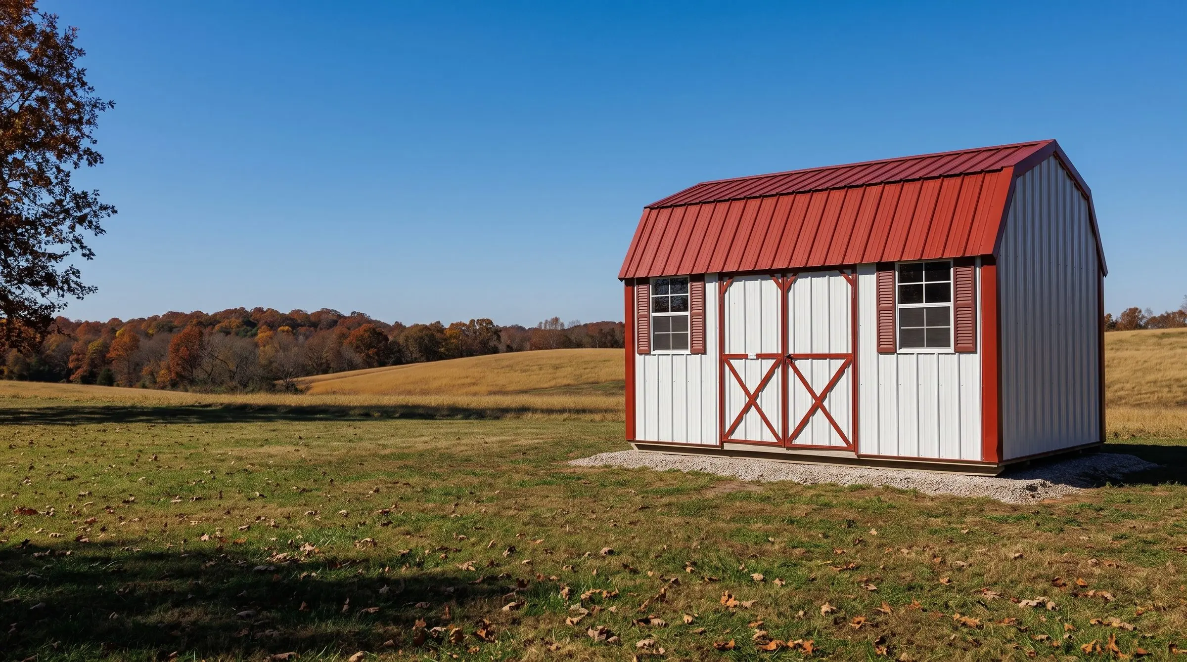 A white metal lofted garden barn with a red roof and red trim, set in a fall field