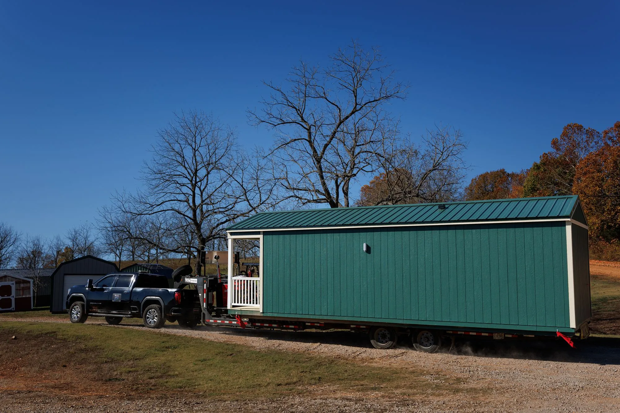 A pickup truck towing a long green building