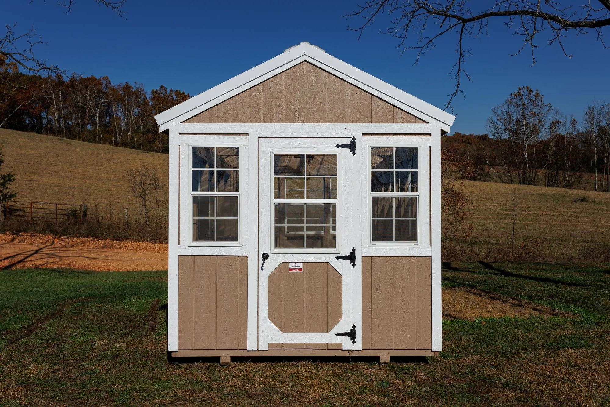 Greenhouse with tan siding with white trim and windows down both sides