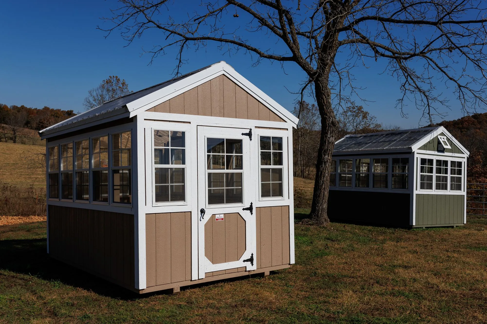 Greenhouse with tan siding with white trim and windows down both sides