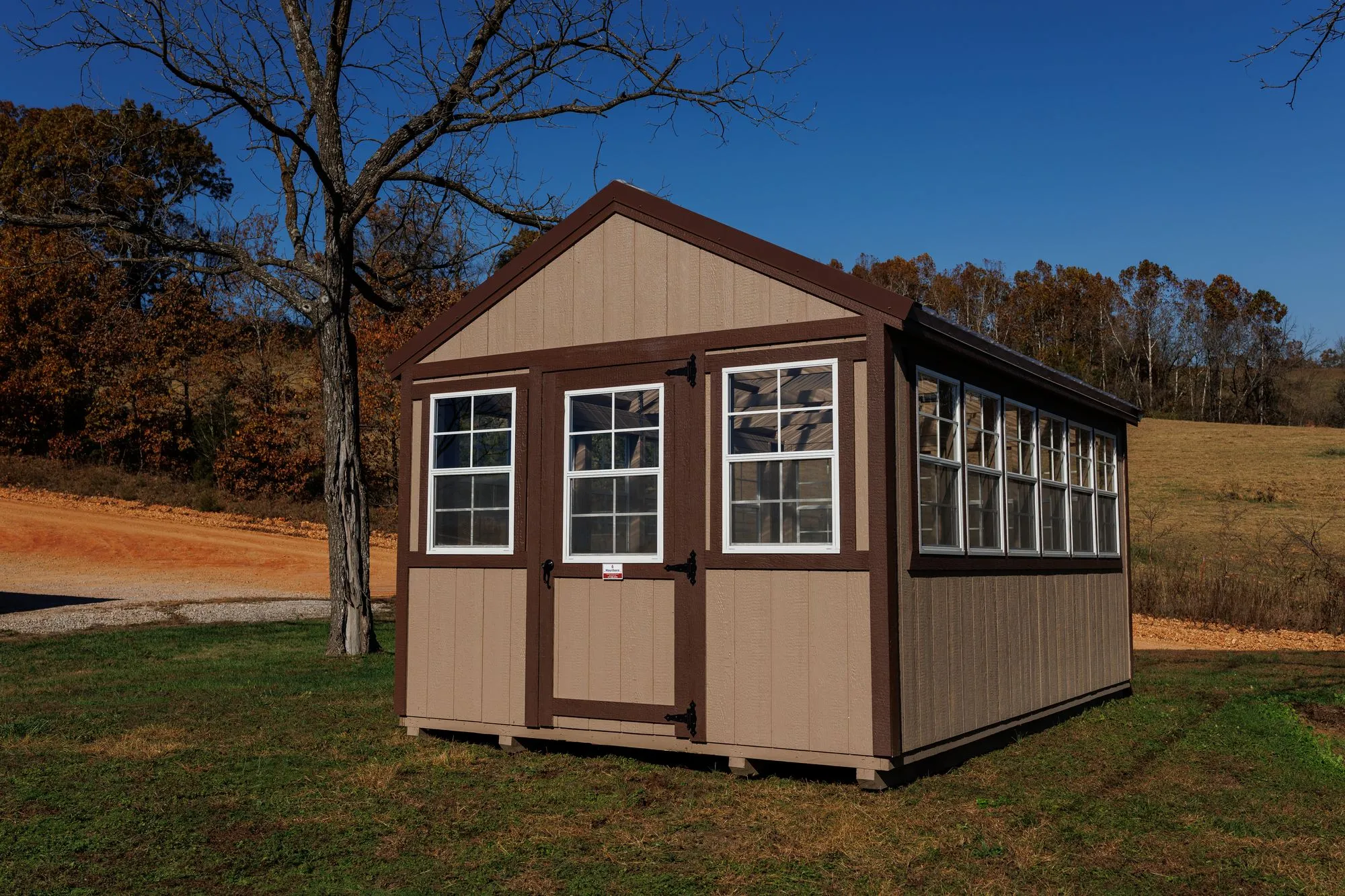 Greenhouse with tan siding with brown trim and a clear corrugated roof