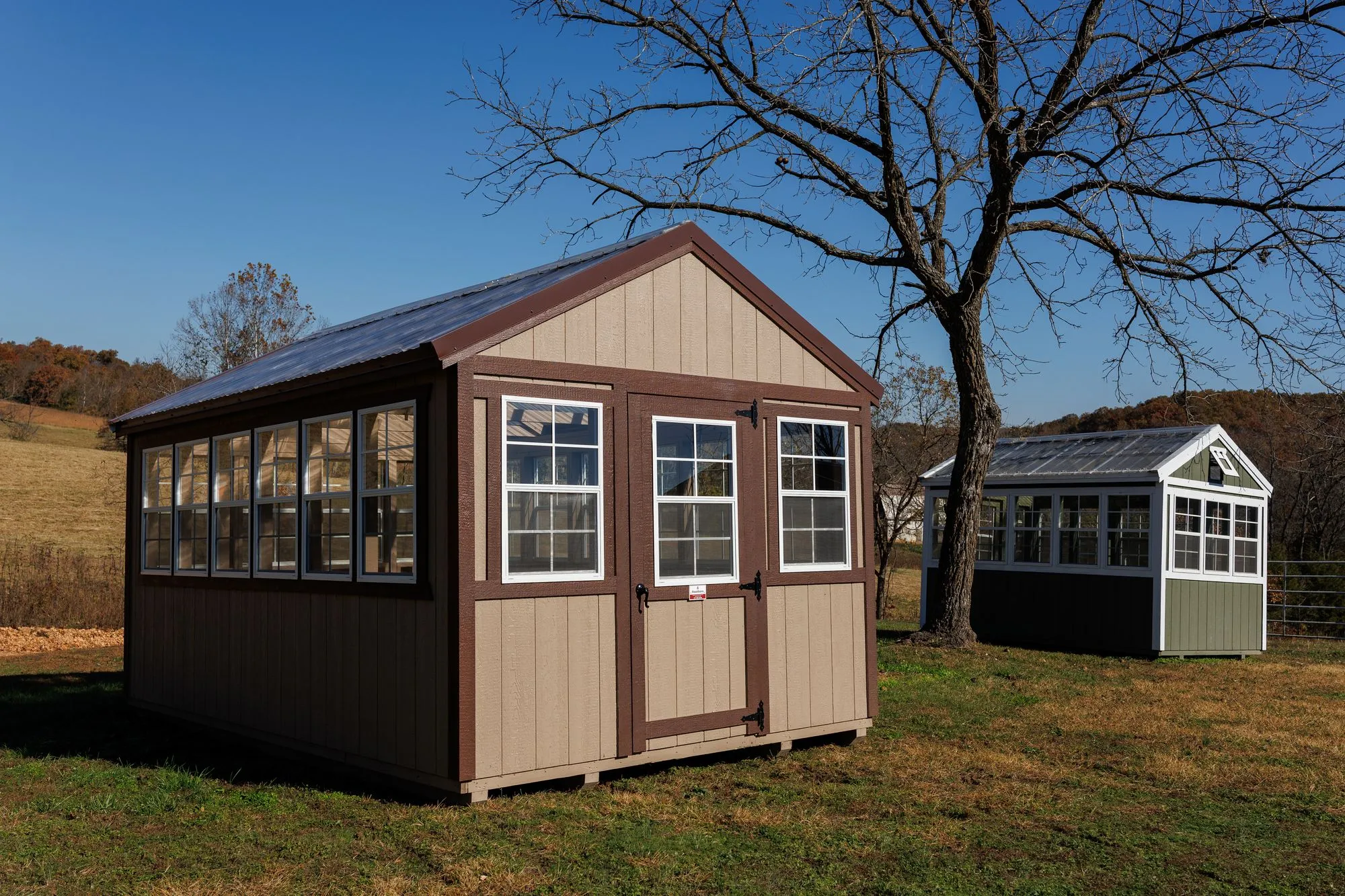 Greenhouse with tan siding with brown trim and a clear corrugated roof