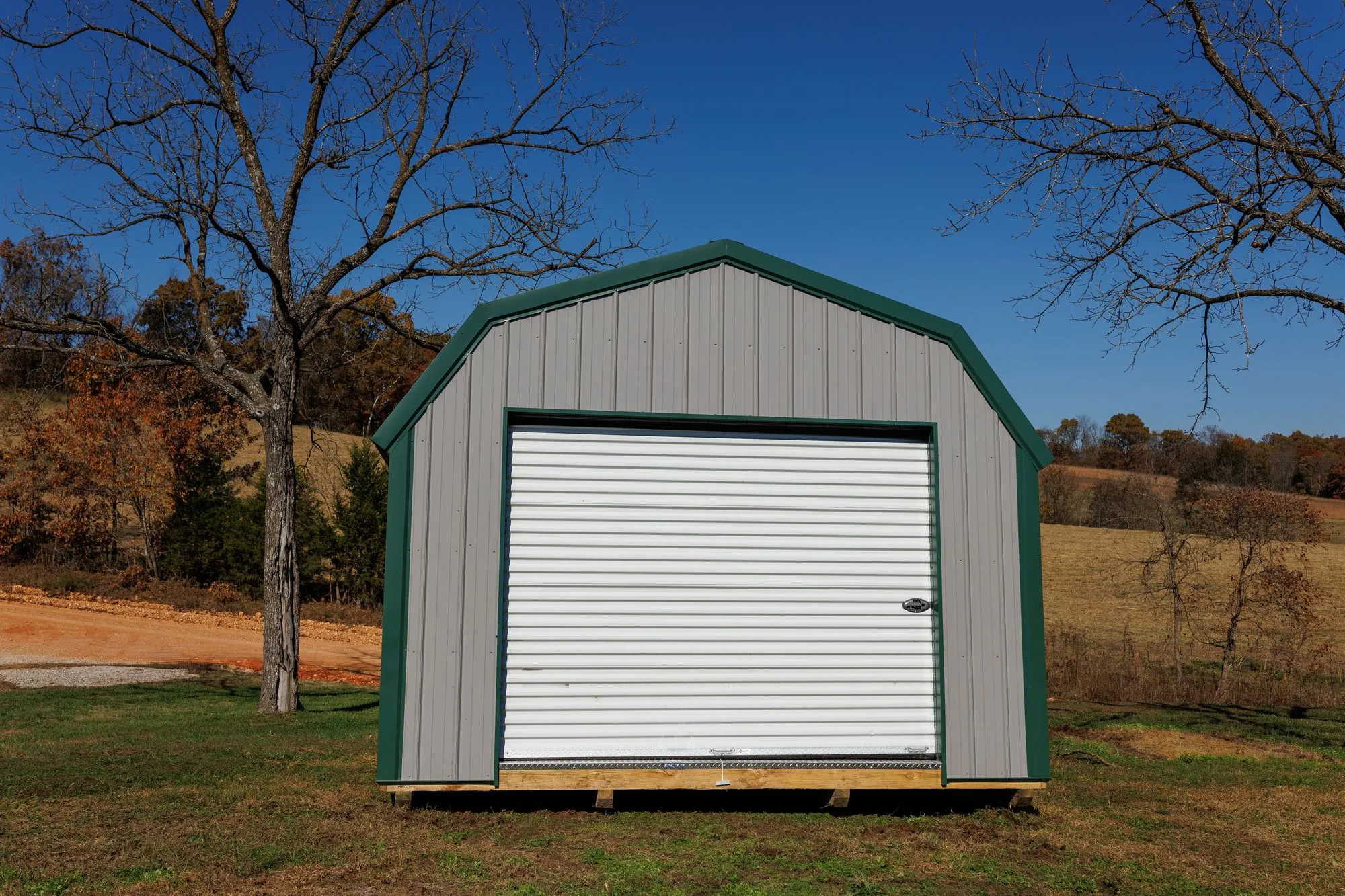 Lofted Garage with gray metal siding with green trim and roof