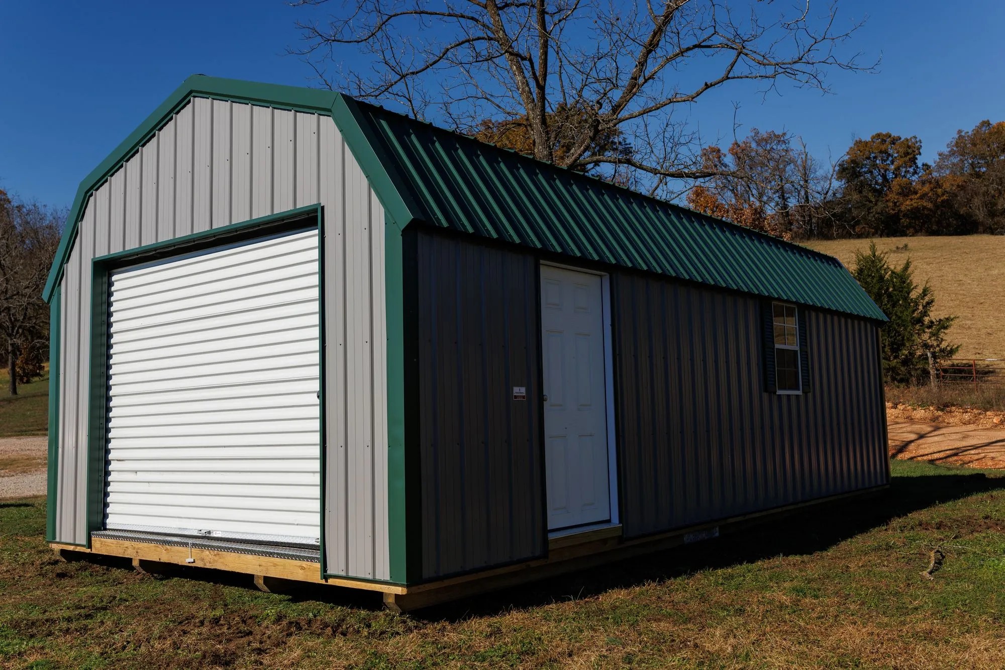 Lofted Garage with gray metal siding with green trim and roof