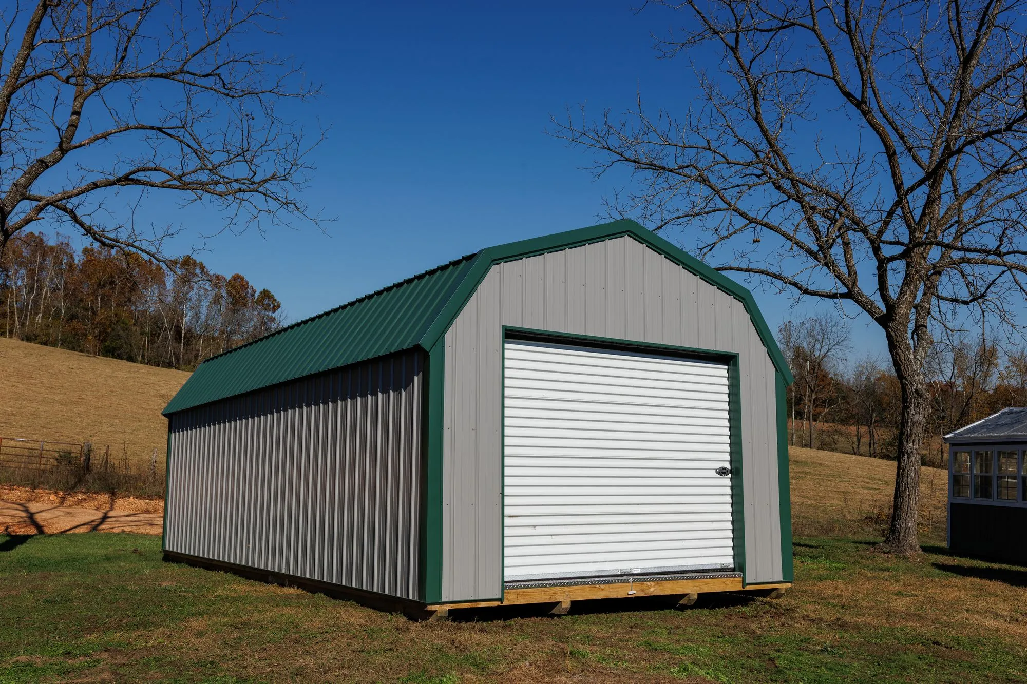 Lofted Garage with gray metal siding with green trim and roof