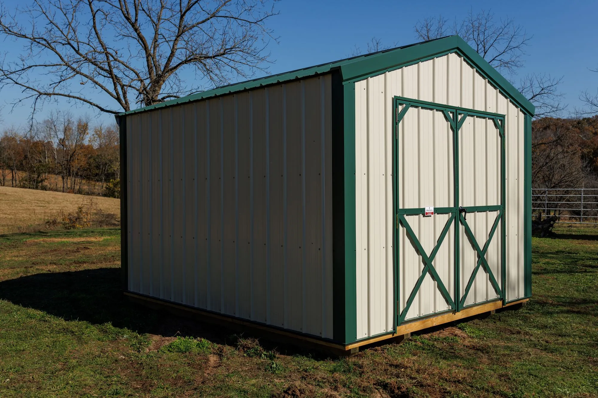 Utility Shed with ivory metal siding with green trim and roof, green X-braced doors