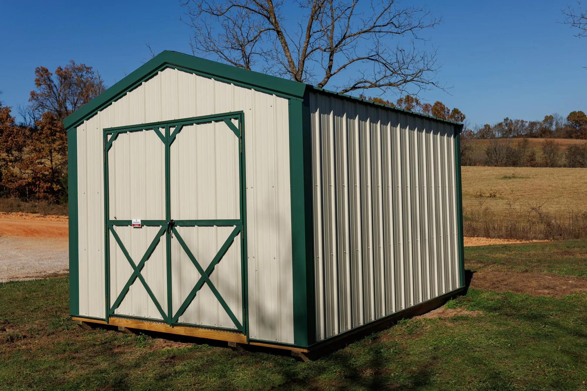 Utility Shed with ivory metal siding with green trim and roof, green X-braced doors