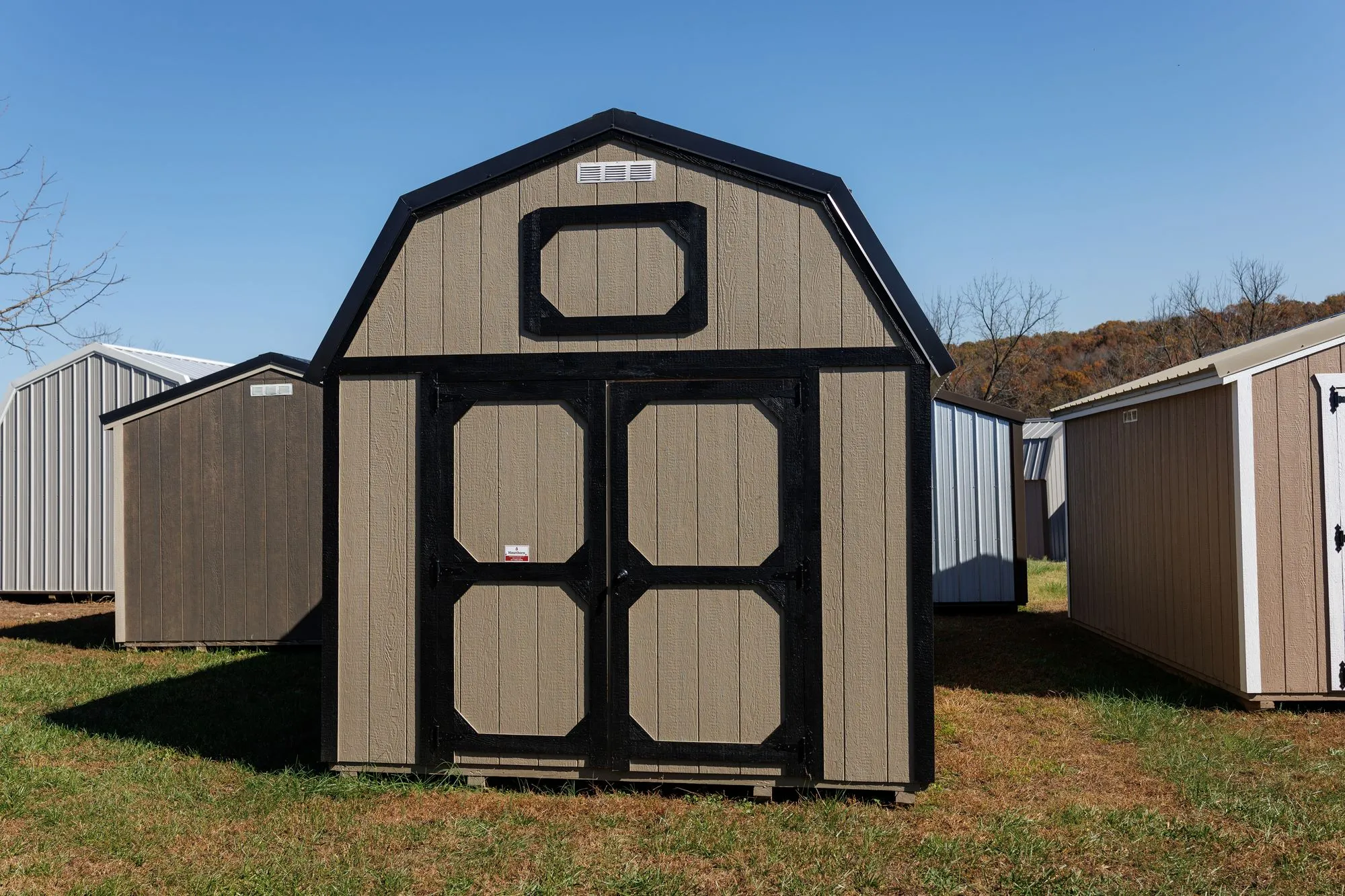 Lofted Barn with tan siding with black trim and roof, octagon-panel doors