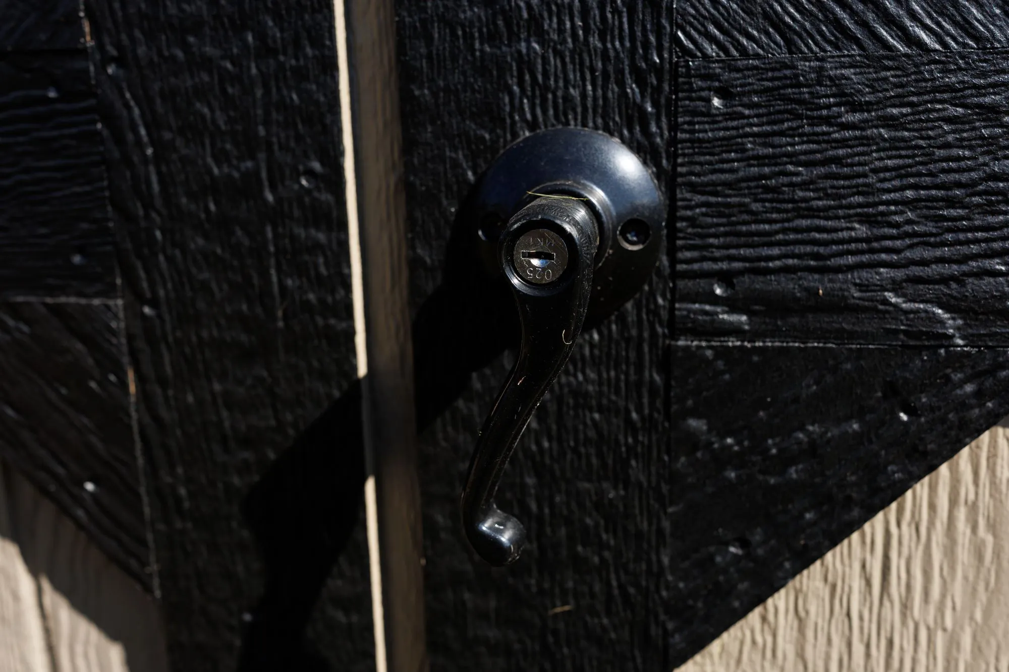 Close-up of a keyed door handle on a black-painted door