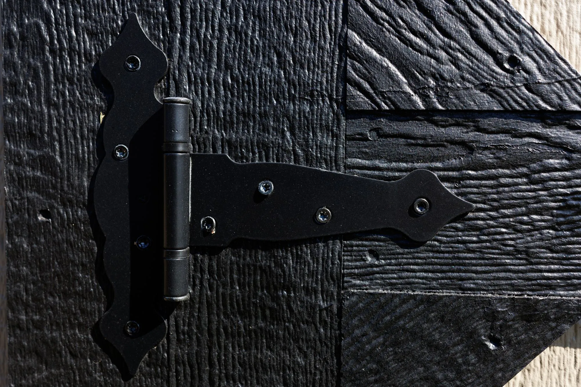 Close-up of a black strap hinge on a painted door