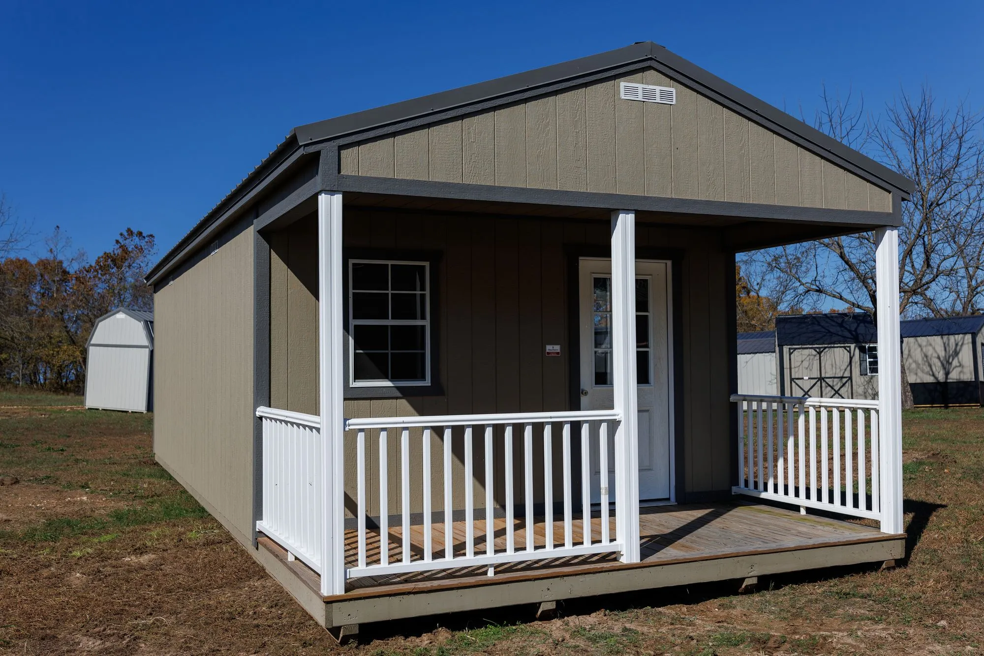 A cabin with a covered front porch and white railings