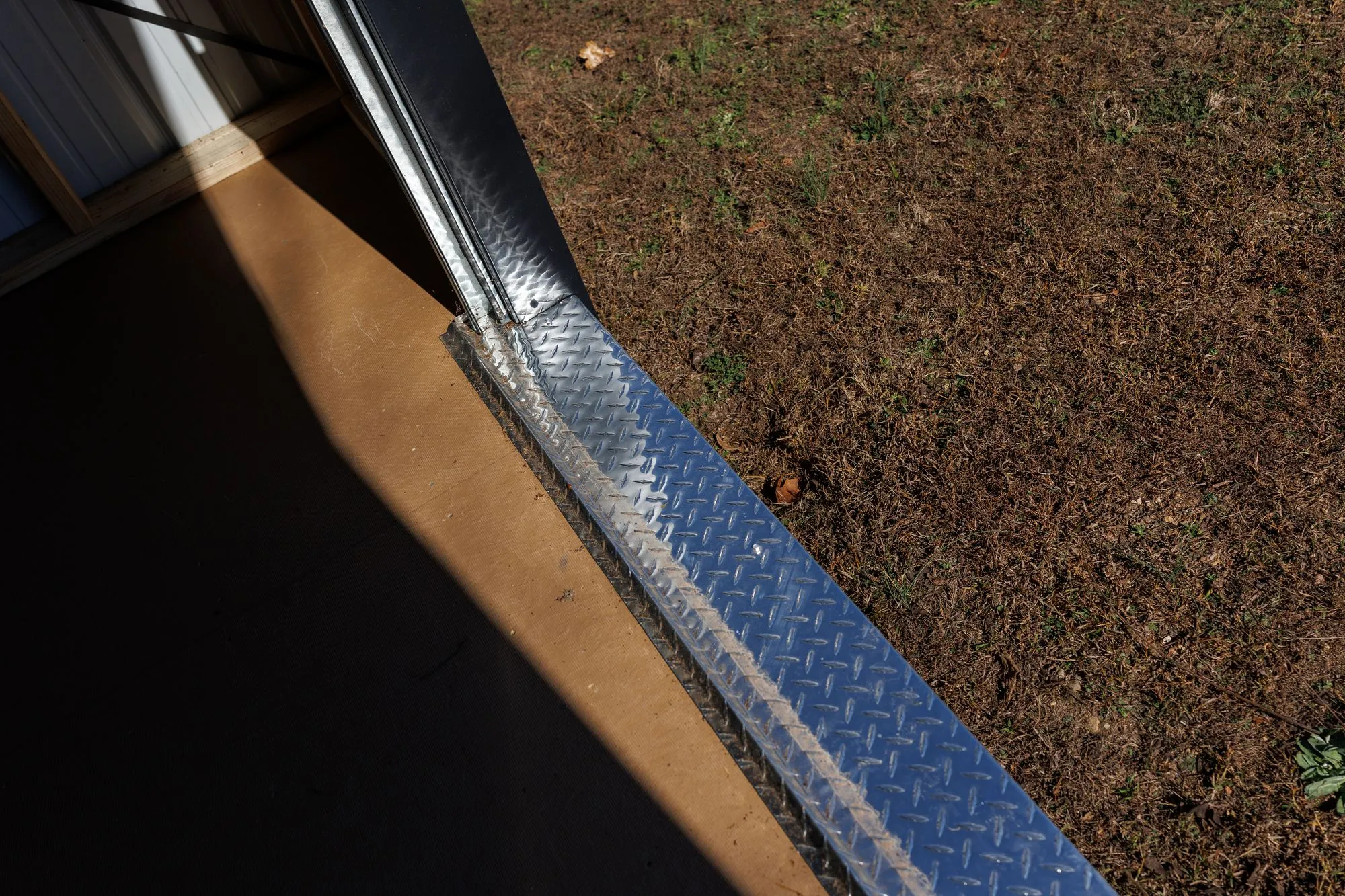 Close-up of the aluminum diamond-plate threshold at a doorway