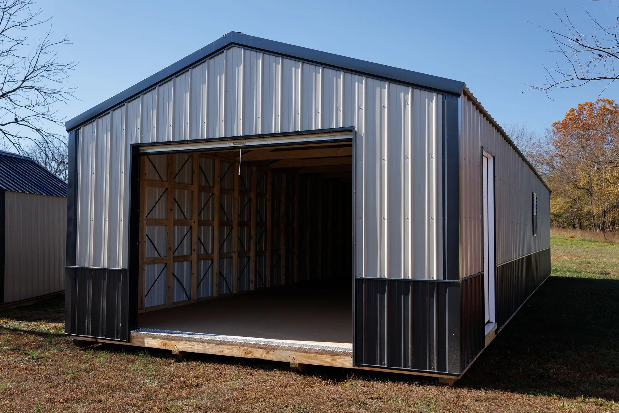Portable Garage with silver metal siding with a black base, black trim and roof