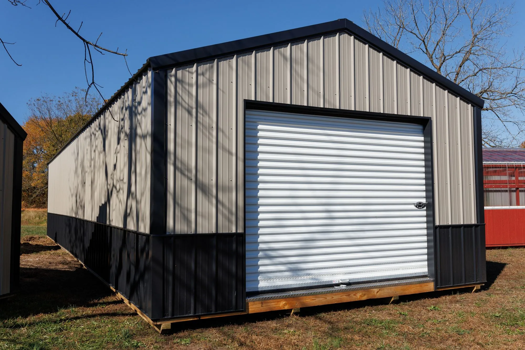 Portable Garage with silver metal siding with a black base, black trim and roof