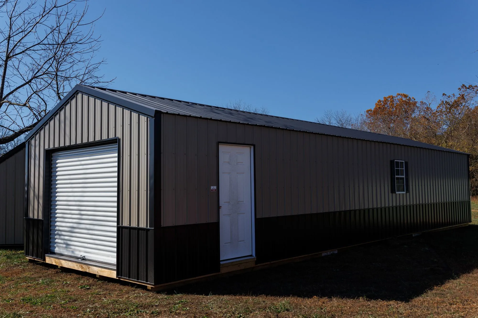 Portable Garage with silver metal siding with a black base, black trim and roof