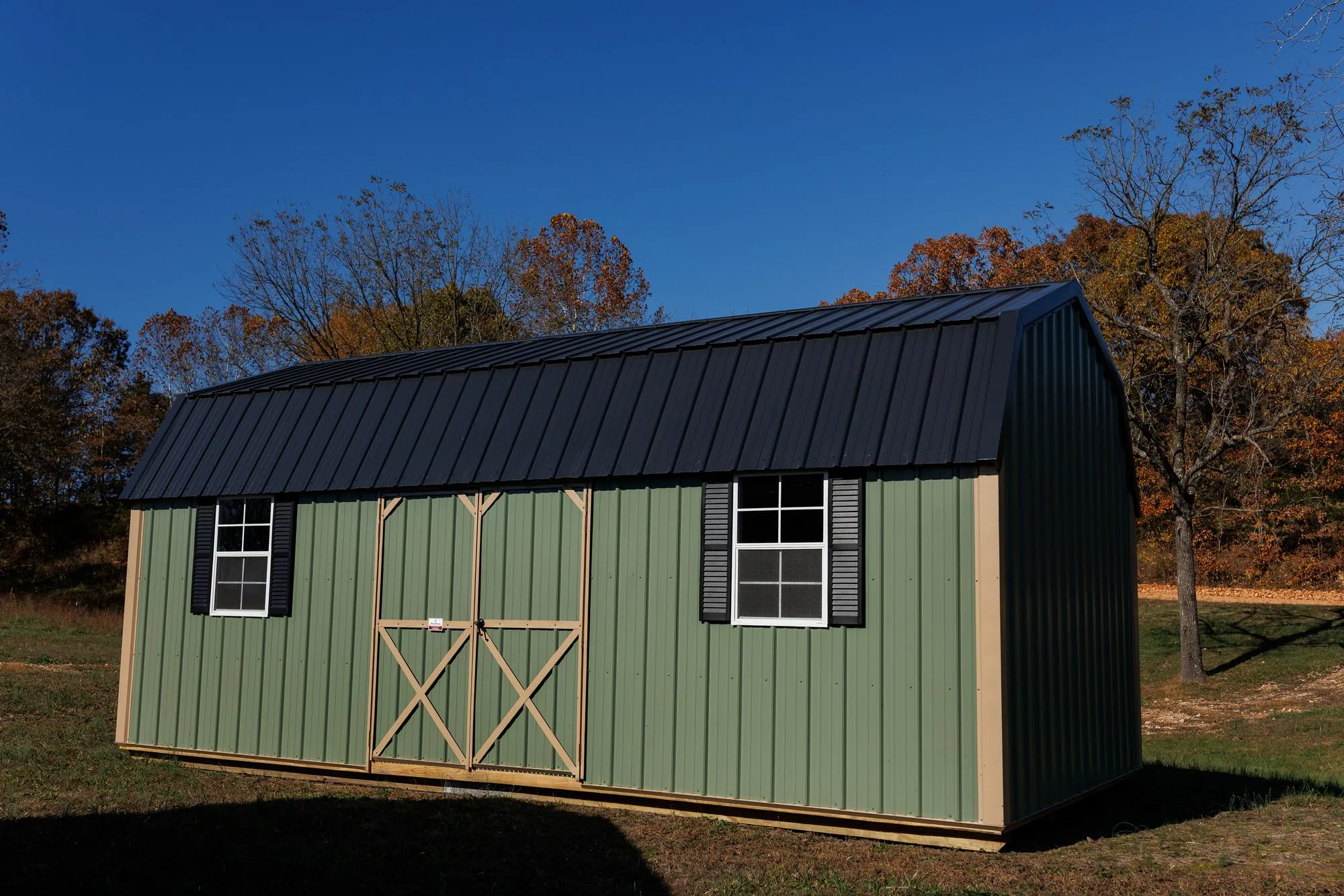 Lofted Garden Barn with sage-green metal siding, tan trim, black roof