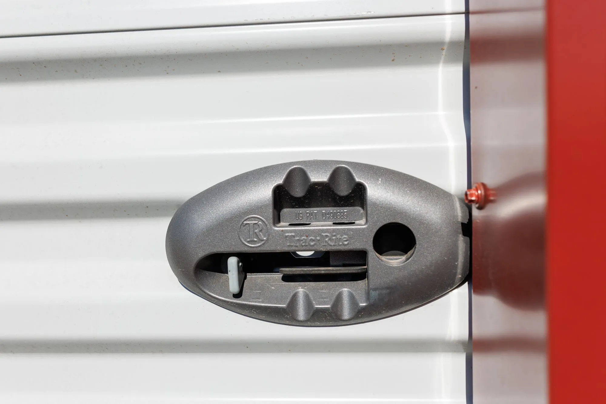Close-up of the roll-up door latch on a white metal garage with red trim