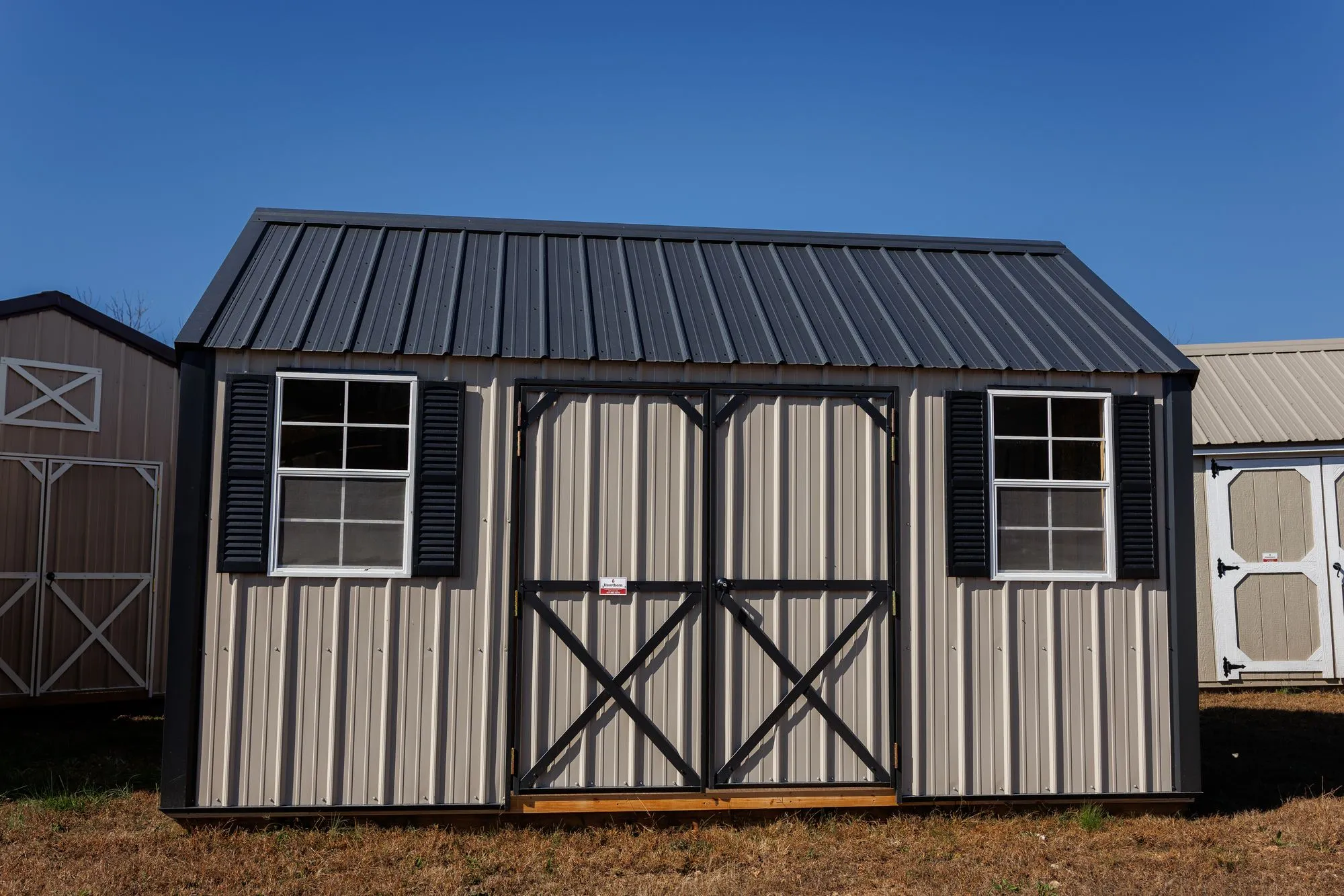 Lofted Garden Shed with clay metal siding, black trim and roof, black X-braced doors, two windows