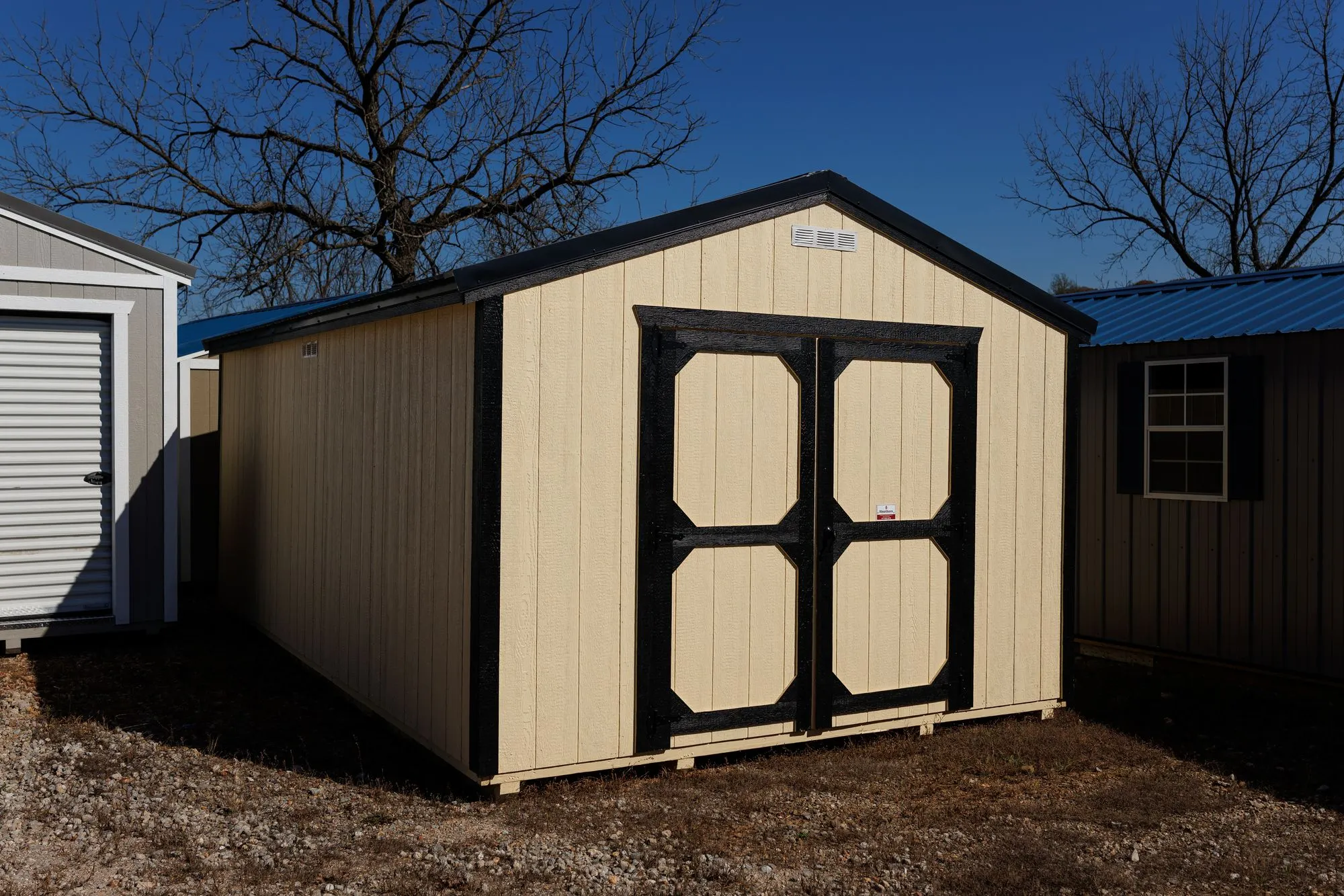 Utility Shed with cream siding, black trim and roof, black-framed octagon-panel doors