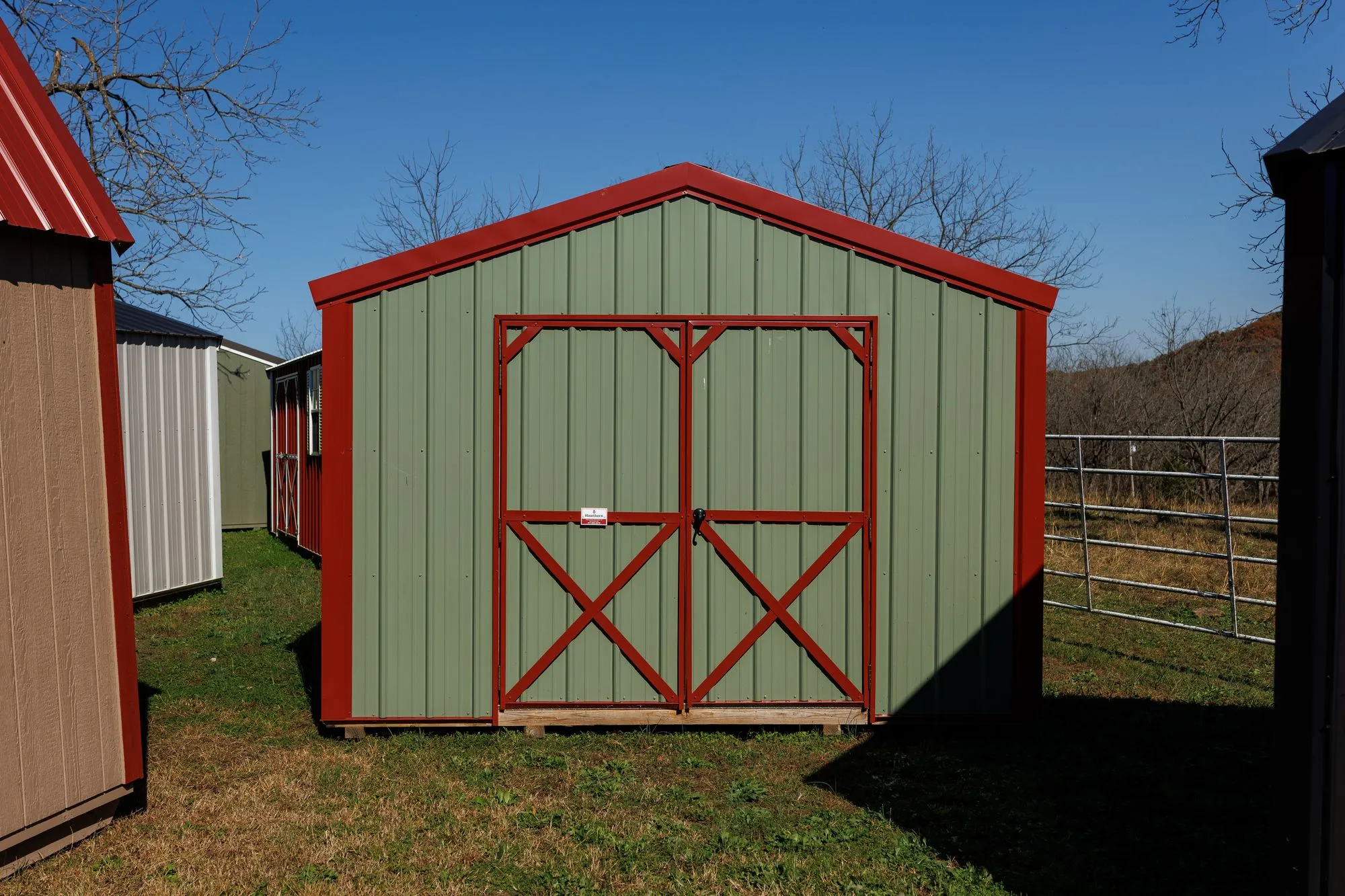 Utility Shed with sage metal siding, red trim and roof, red X-braced doors