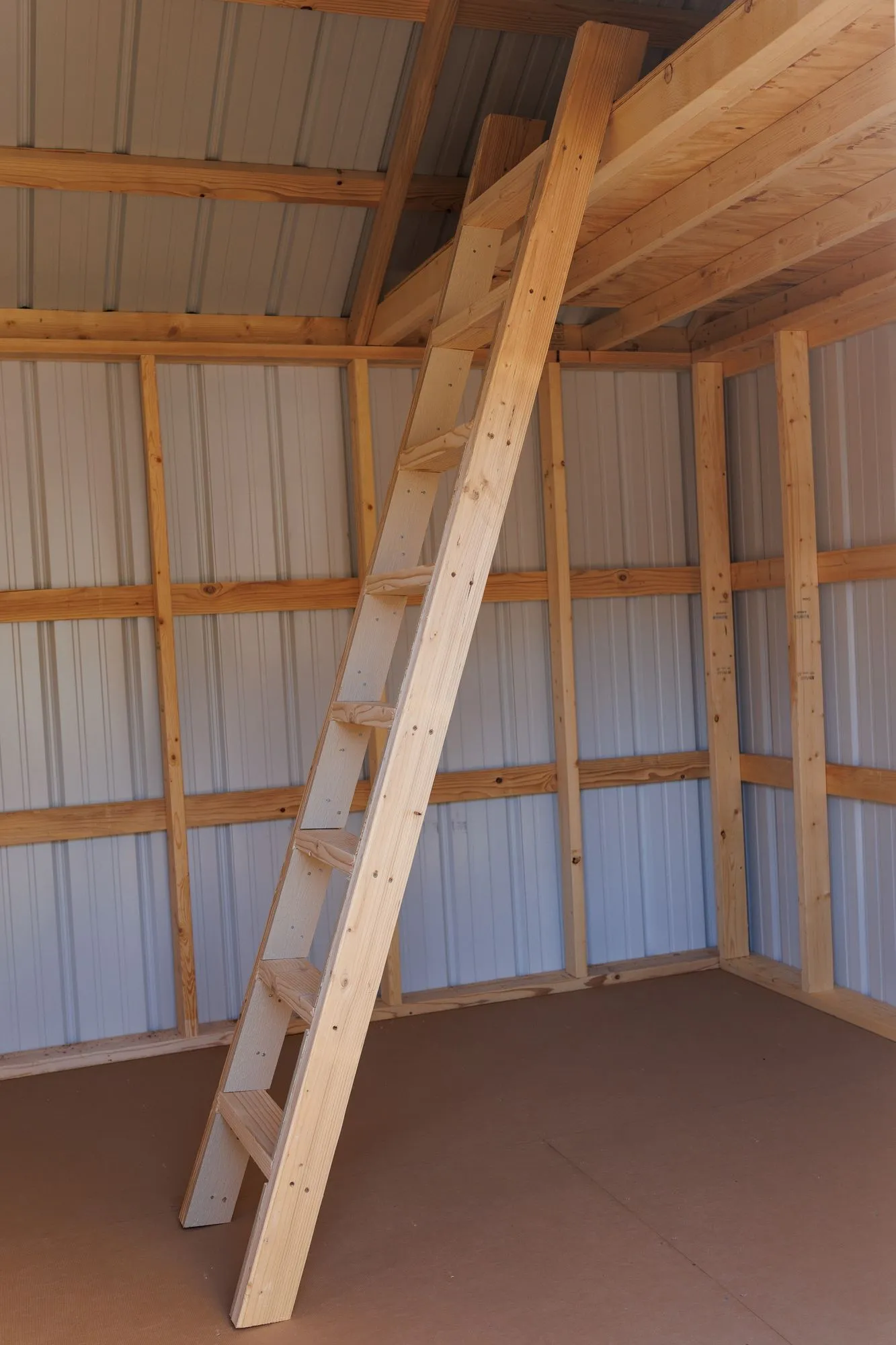 A loft deck and wooden ladder inside a lofted building