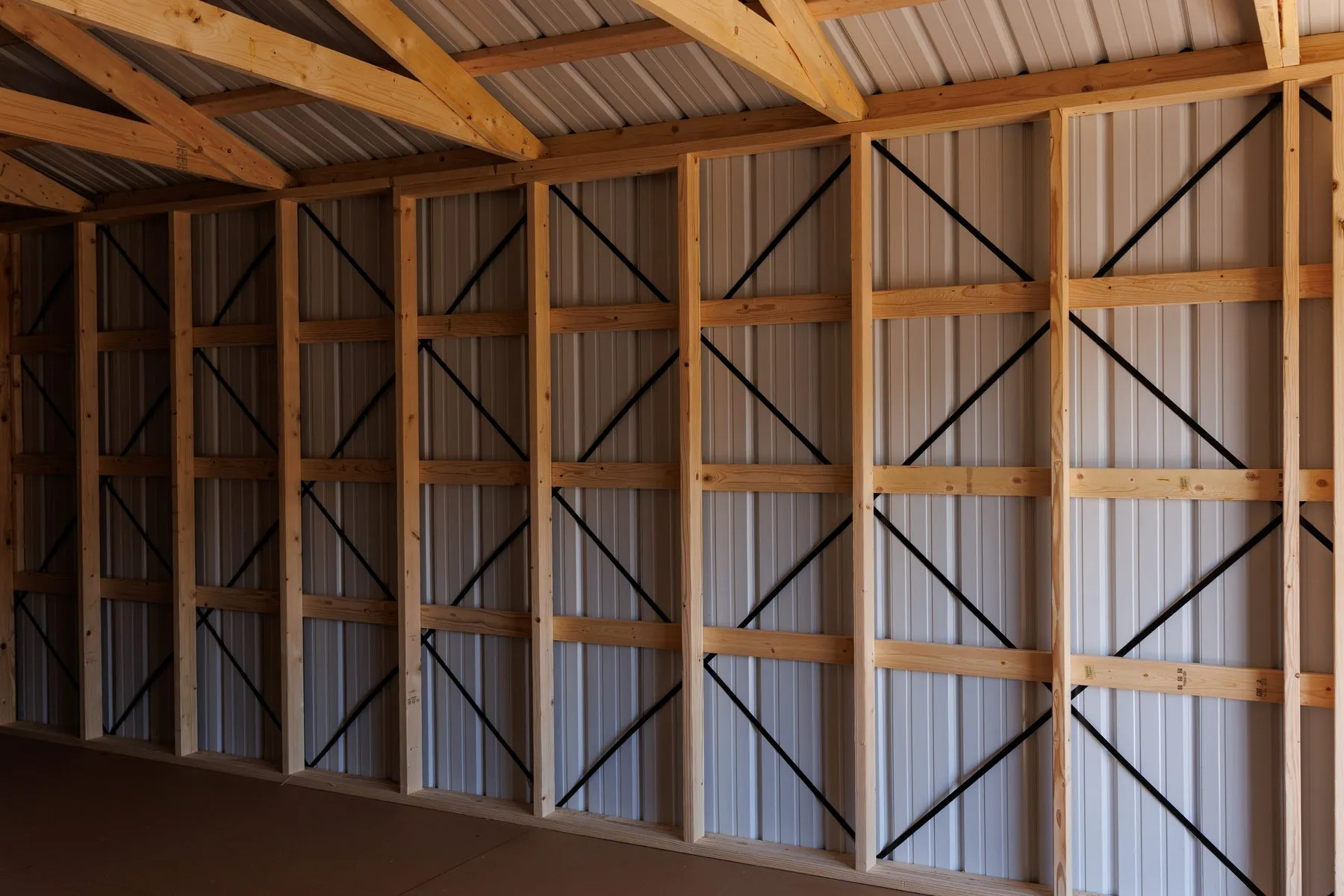 A long wall of studs, girts and black diagonal bracing inside a building